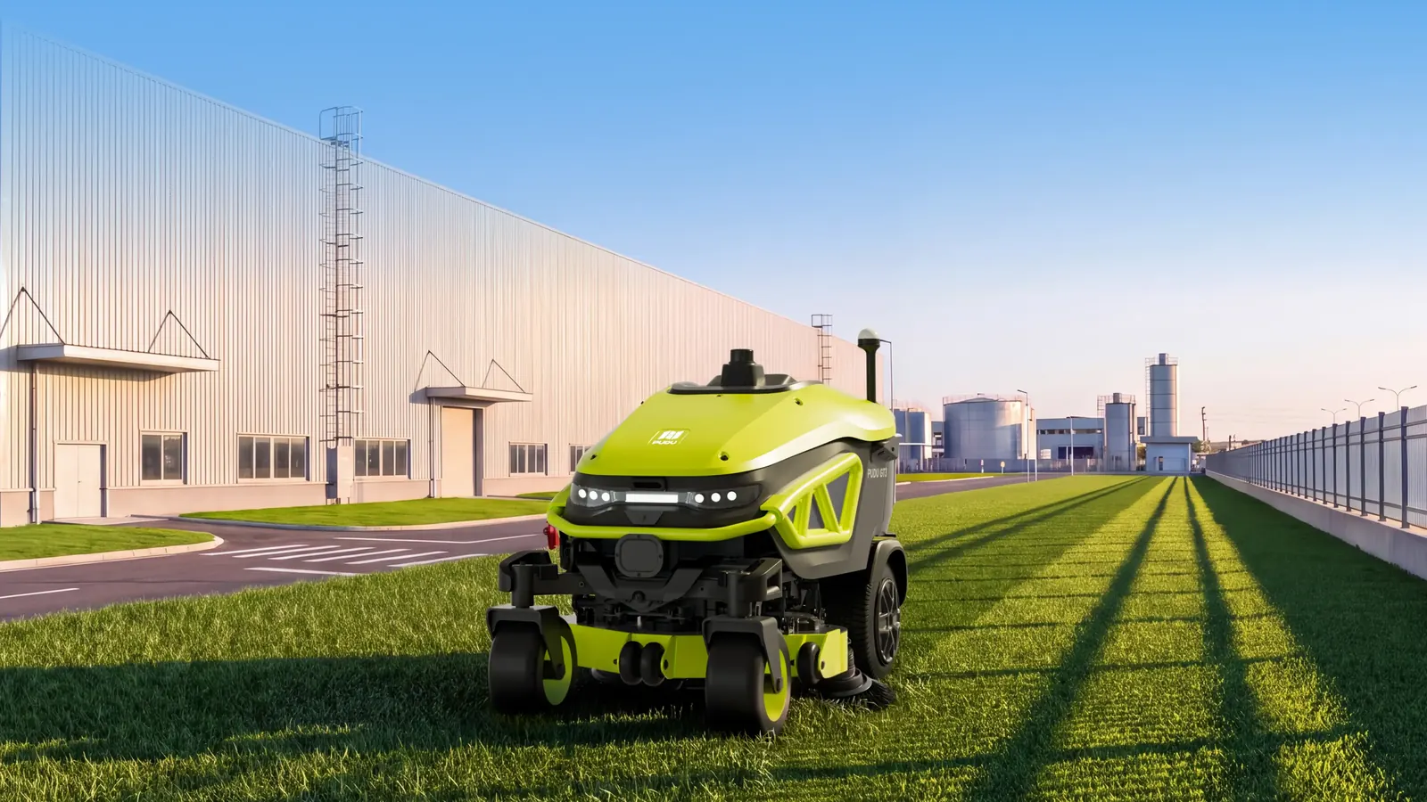 Robot cortacésped PUDU GT3 sobre césped junto a una nave industrial, con la luz del atardecer